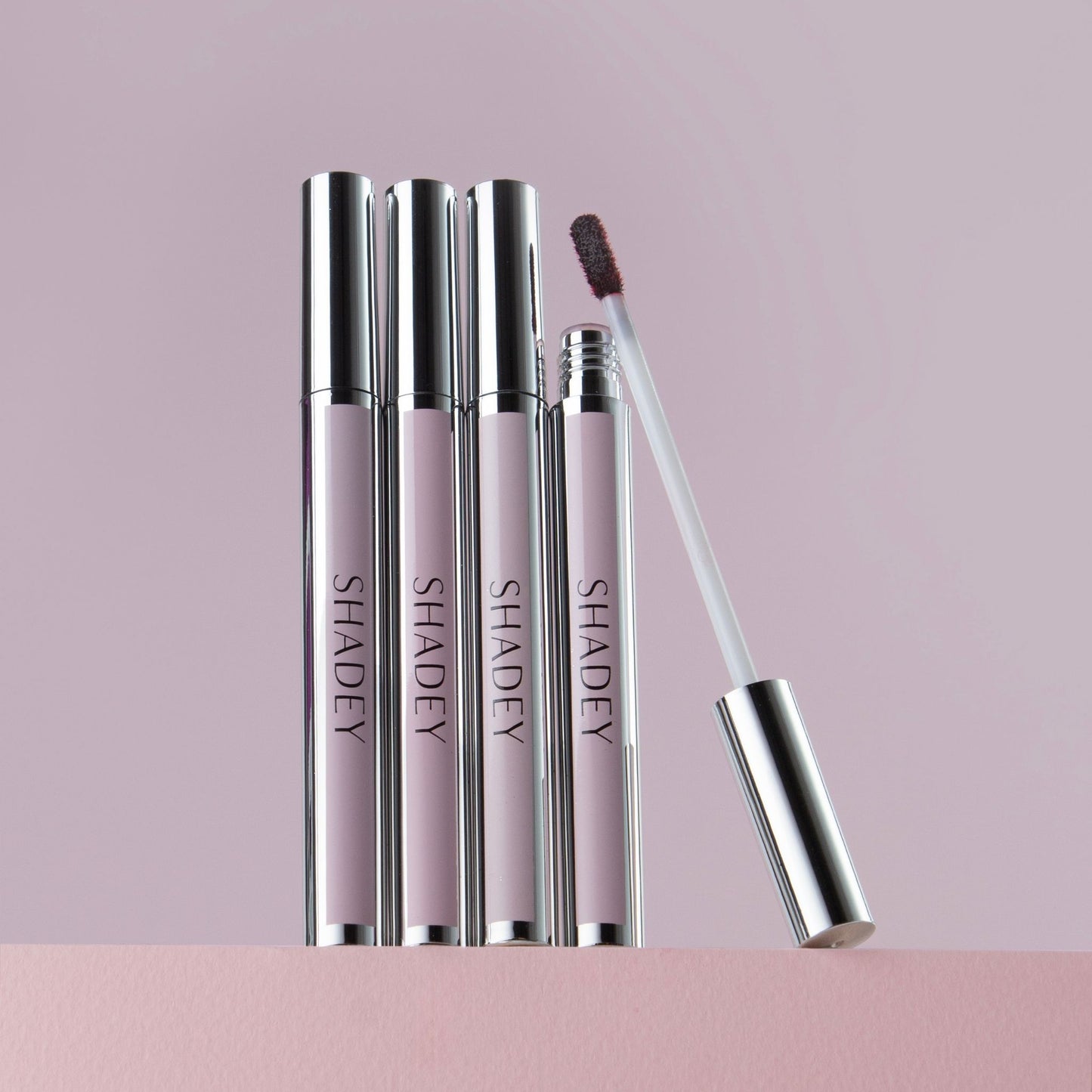 Set of 'SHADEY' lip products on a pink background