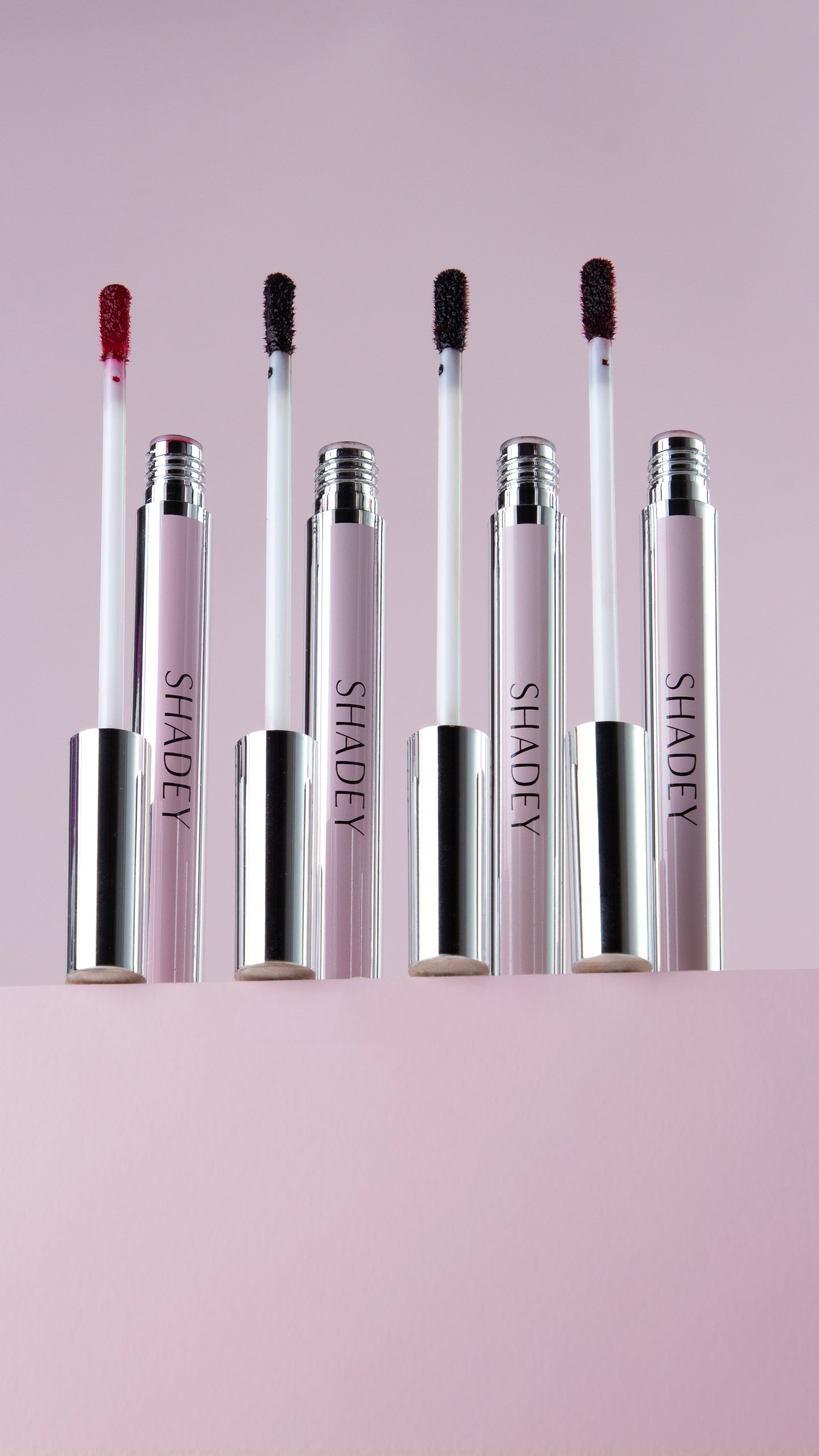 Set of lip staines with applicators on a light pink background